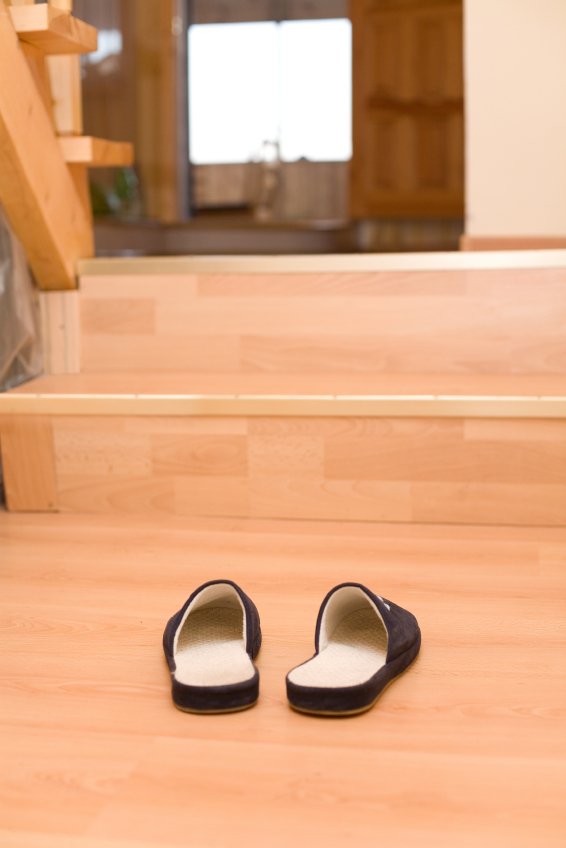 A pair of slippers resting on a wood-grain floor installed over an electric radiant floor heating system.