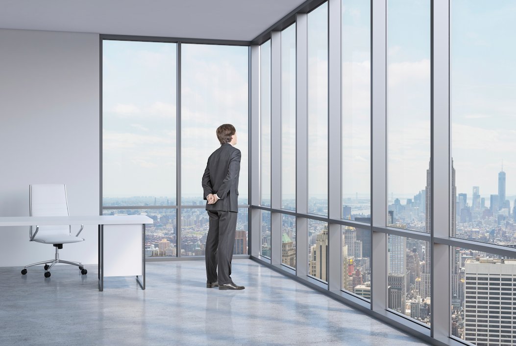 A modern high-rise office with polished concrete floors and floor-to-ceiling windows overlooking a city skyline.