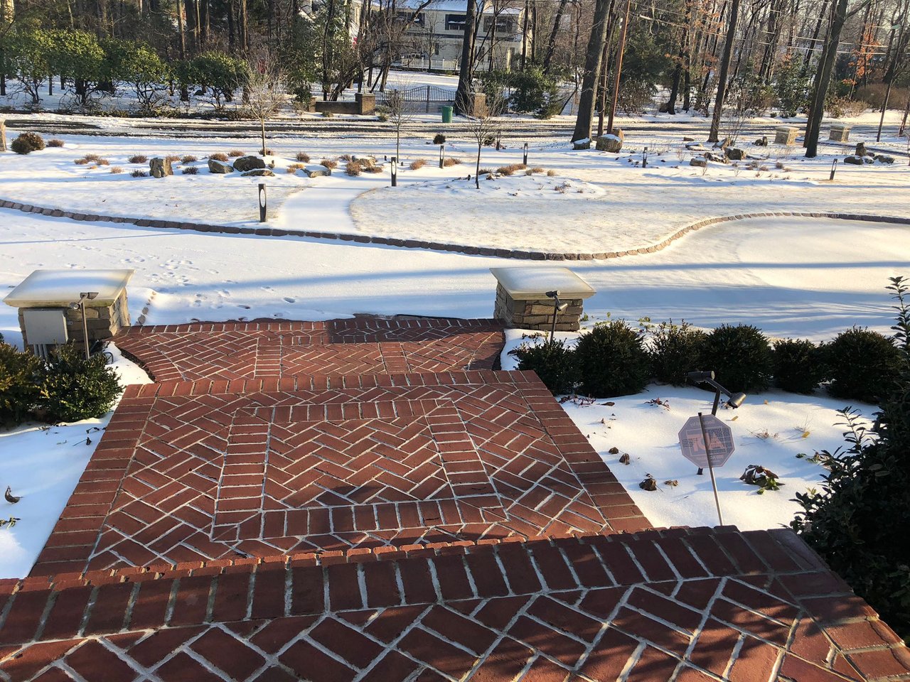 Heated red brick herringbone walkway and steps clear of snow during a winter day.