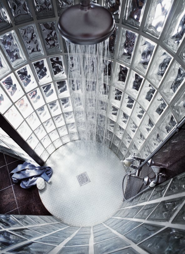 A walk-in shower with a circular mosaic tile floor featuring a central drain and concealed electric radiant floor heating.