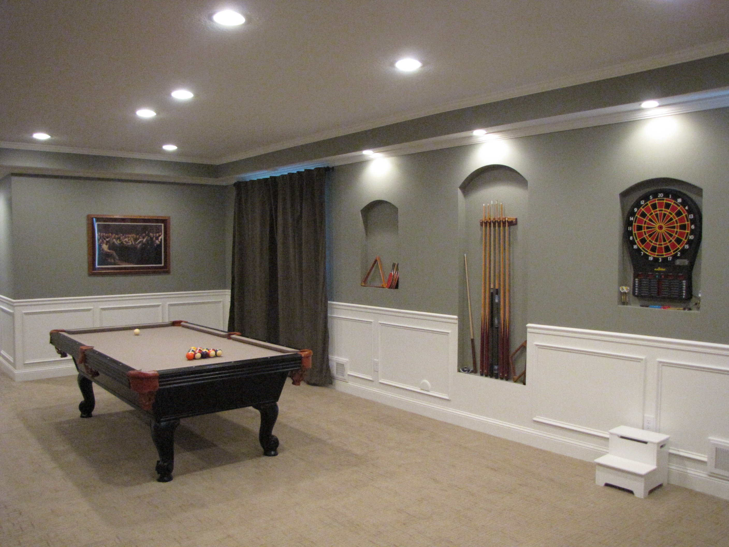 A finished basement recreation room with electric radiant floor heating installed beneath light-brown carpeting.
