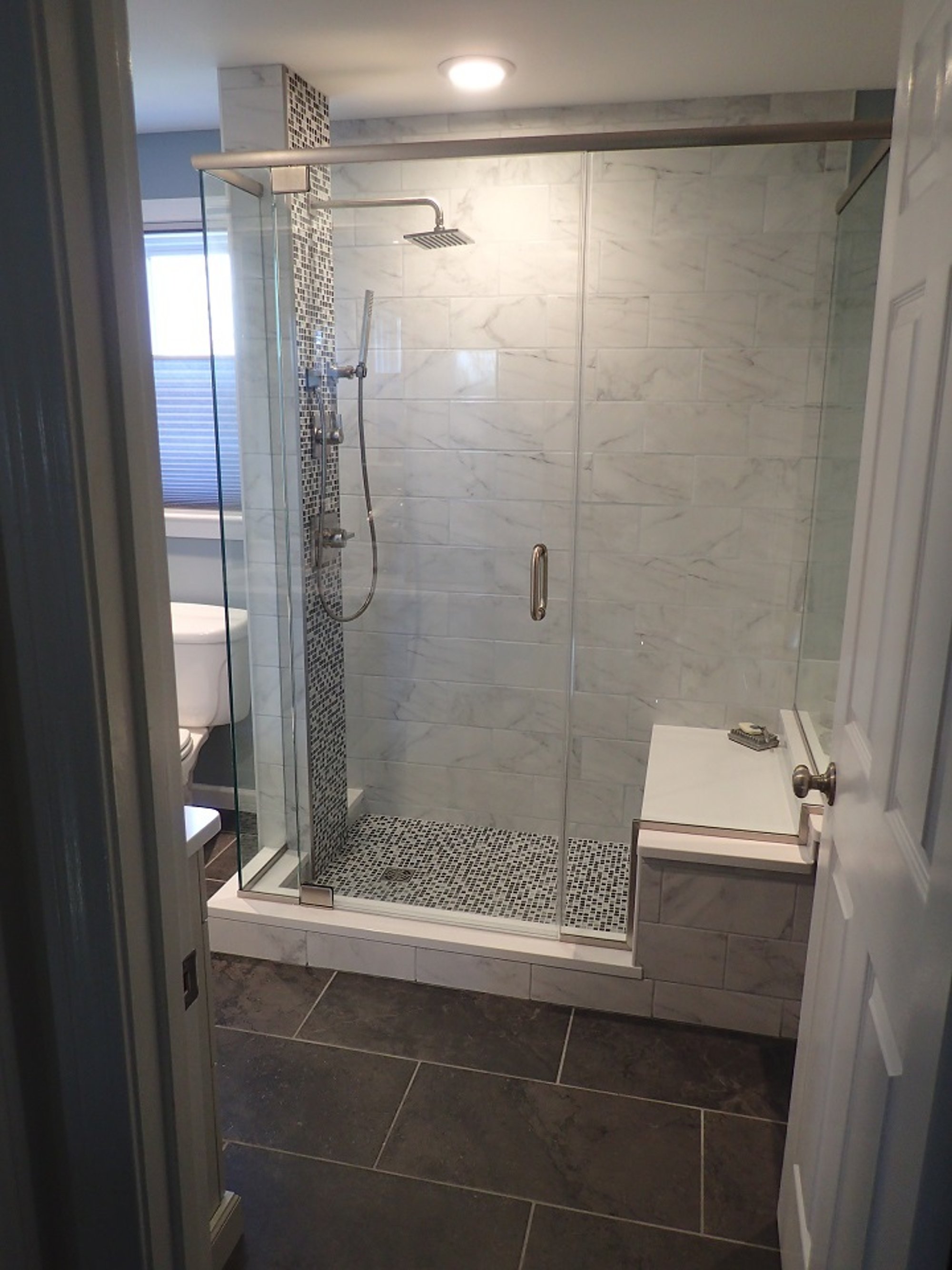 Remodeled bathroom with heated tile floors and shower with bench