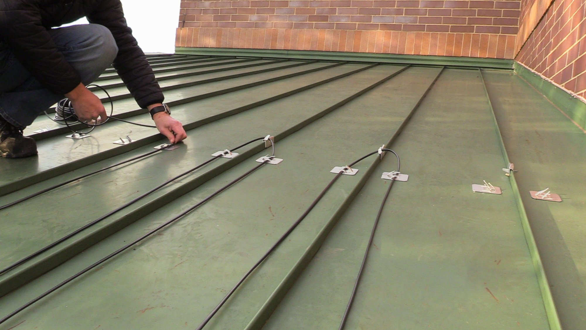 Roof and Gutter installation for WarmlyYours Office hooking wire into clips