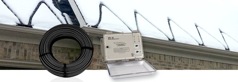 An APS-3C snow and ice melting controller next to a spool of heating cable for a roof and gutter deicing system on a snow-covered building.