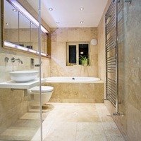 A modern bathroom featuring a wall-mounted ladder-style towel warmer and natural stone tile flooring with electric radiant floor heating.