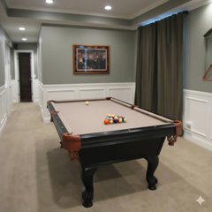 A finished basement game room featuring a billiard table on beige carpeted flooring with sage green walls and white wainscoting.
