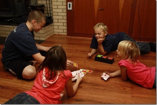 Four children playing a card game on a wood-look floor in a family room equipped with electric radiant floor heating.