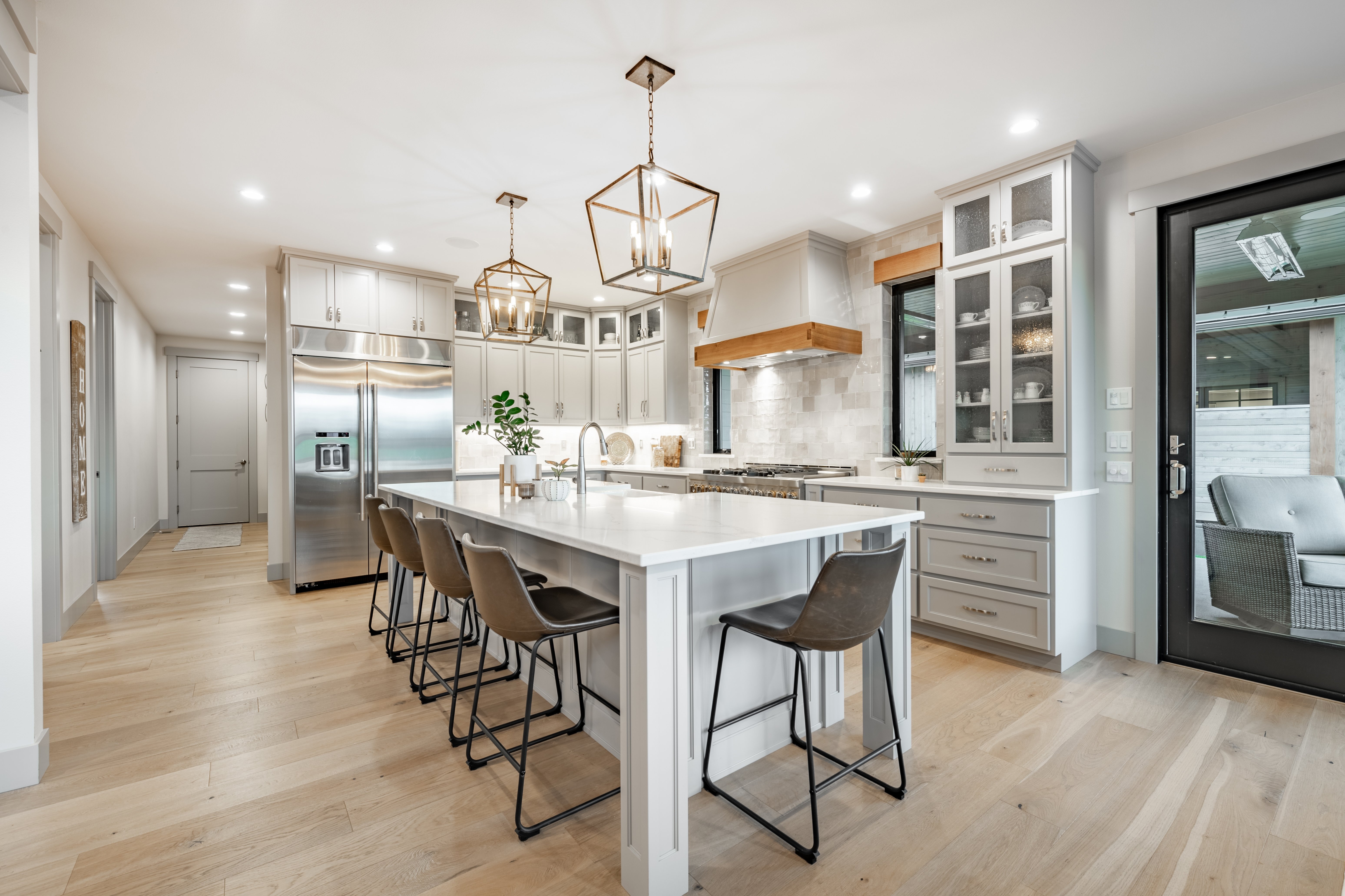 Modern kitchen featuring upgraded hardwood flooring, stainless steel appliances, and white cabinetry.