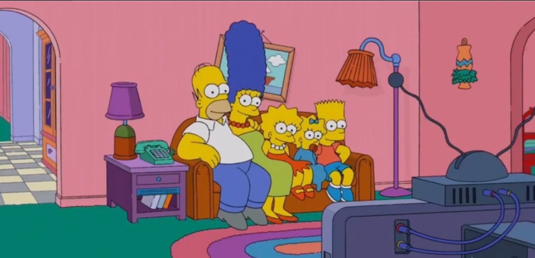 The Simpson family sitting together on their living room couch watching television.