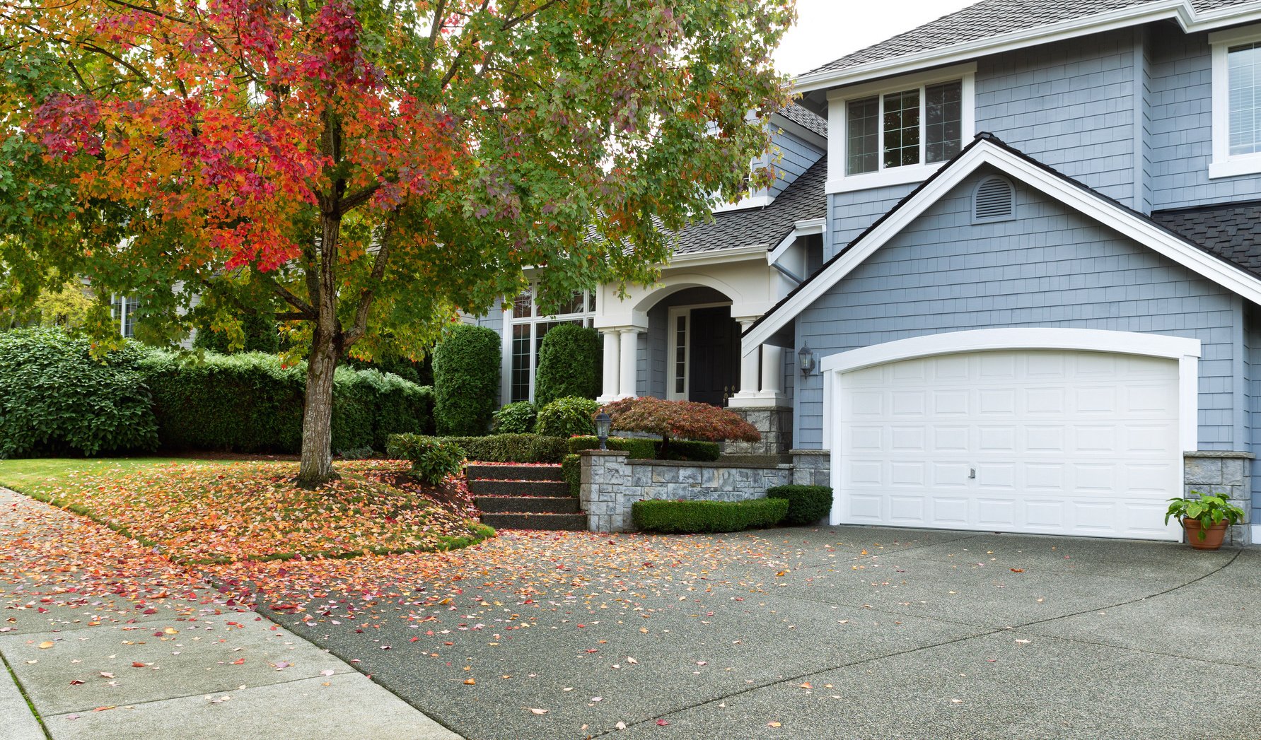 A residential driveway and walkway featuring a snow melting system installed beneath the concrete surface during the autumn season.