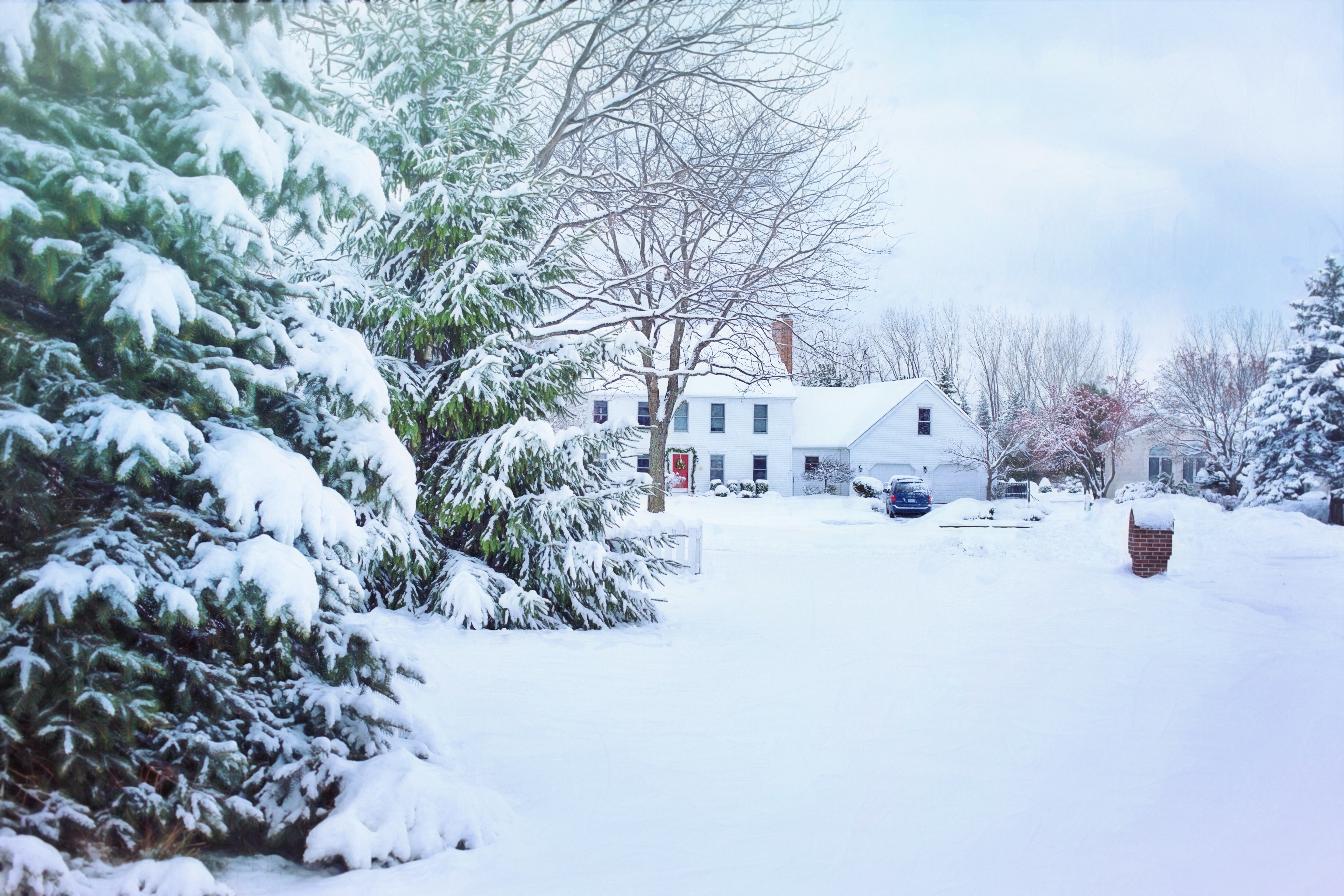 A snow-covered residential driveway and front yard in winter, highlighting the need for a snow melting system.