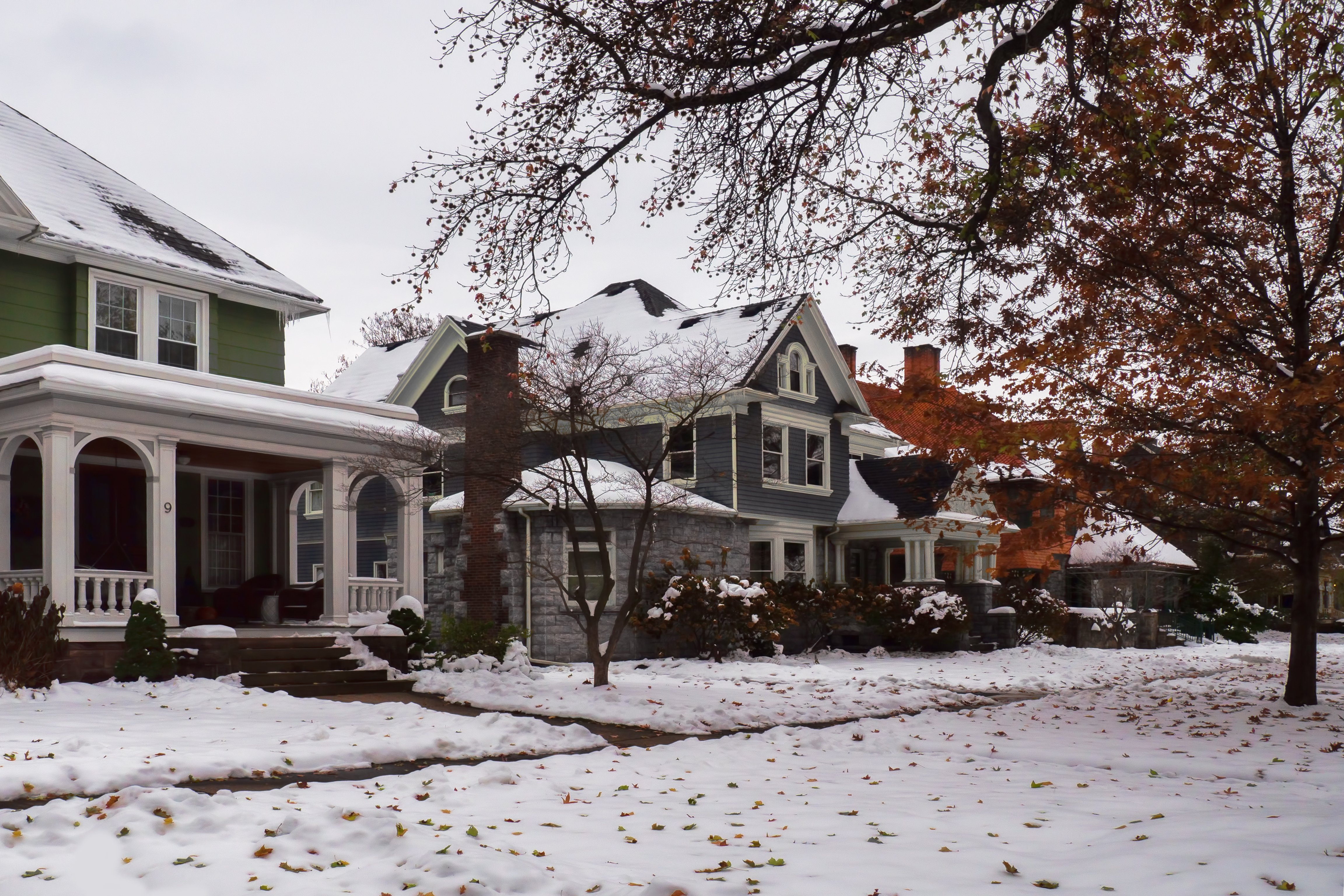 Snow-covered residential home in Rochester, NY, featuring a clear walkway and porch during a winter snowstorm.