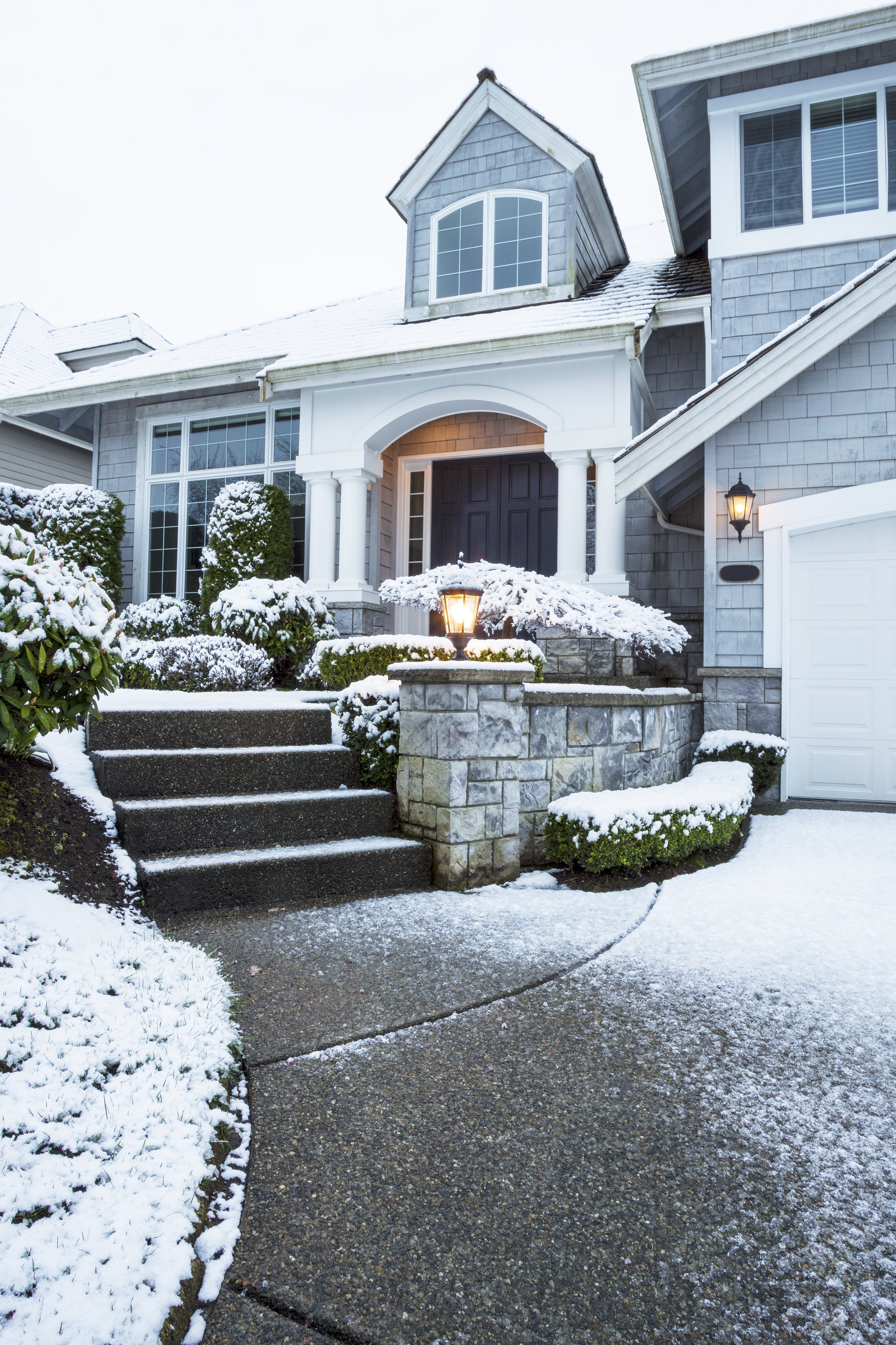 A snow melting system keeps a concrete walkway clear of snow and ice in front of a two-story home during winter.