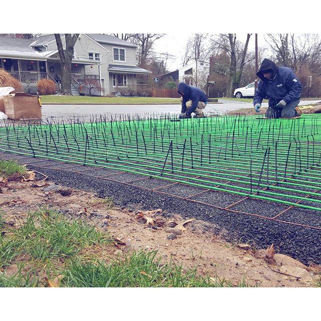 Electric snow melting cables laid out on the base course of an asphalt driveway before the top coat