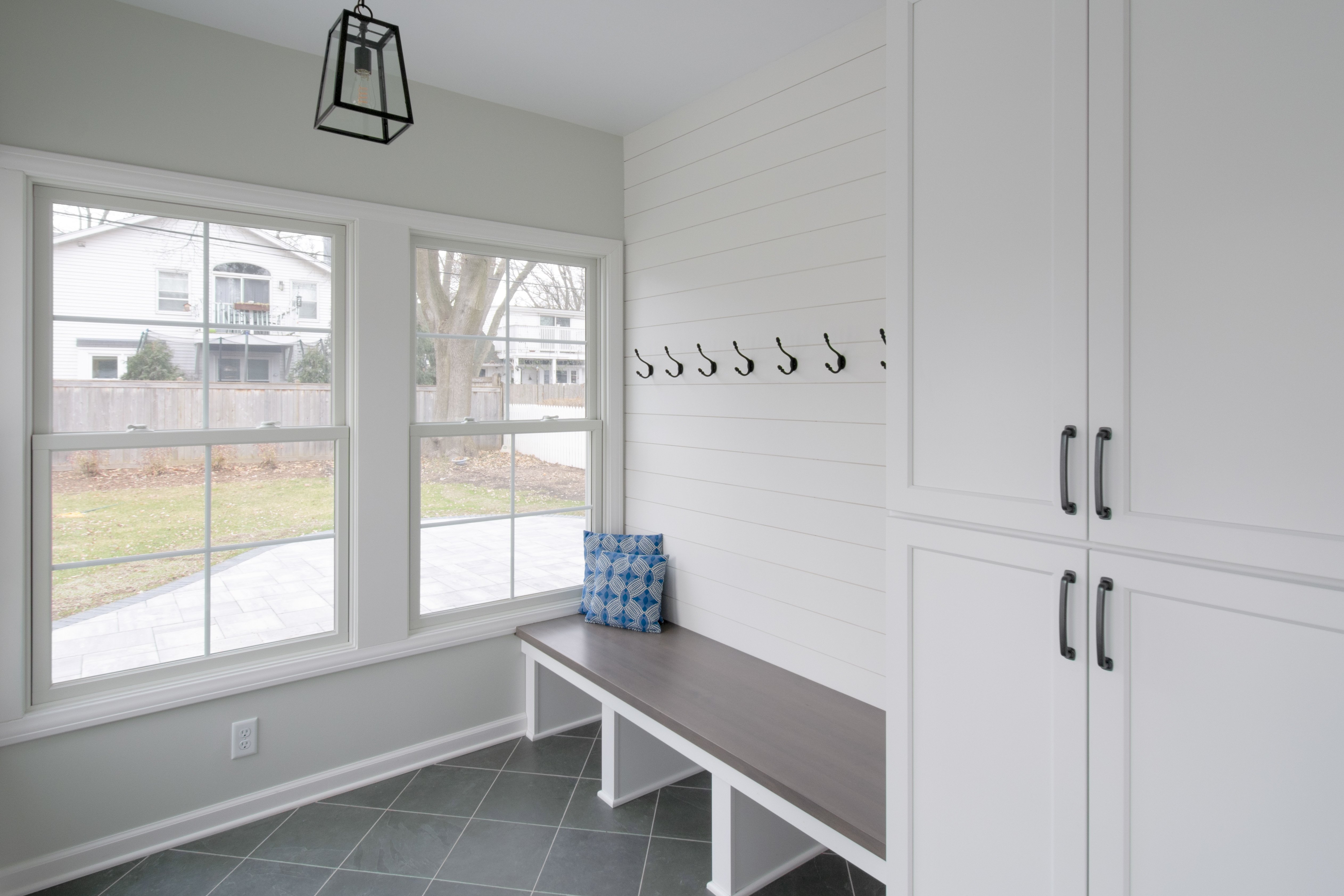 Electric radiant floor heating installed beneath diagonal slate-colored tiles in a sunroom with built-in cabinetry and bench seating.