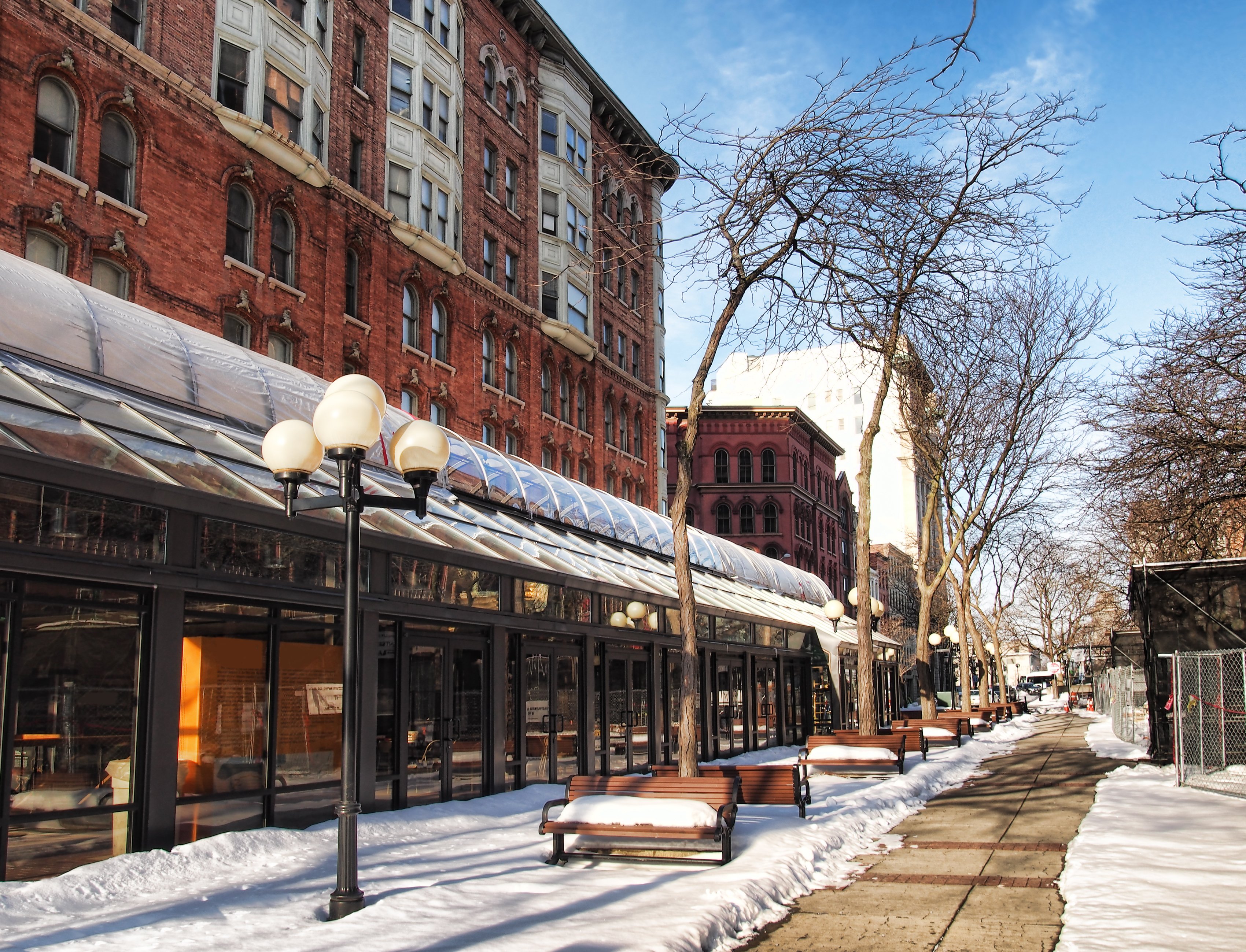 A clear sidewalk path in front of a historic brick building during winter, demonstrating the effectiveness of a snow melting system.