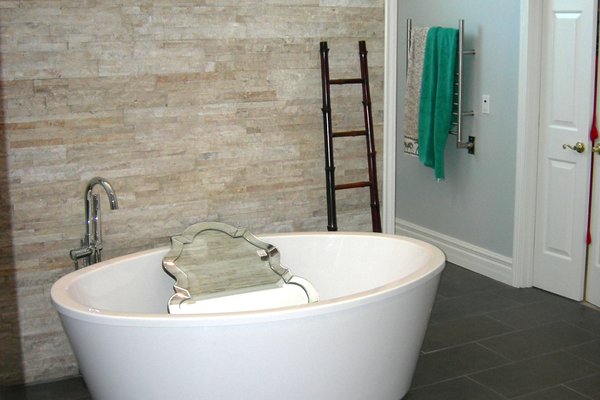 Completed modern bathroom featuring a white freestanding bathtub on dark tiled flooring.