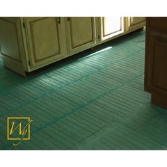 TempZone electric radiant floor heating mesh with blue heating cables on green fiberglass matting installed on a kitchen subfloor.