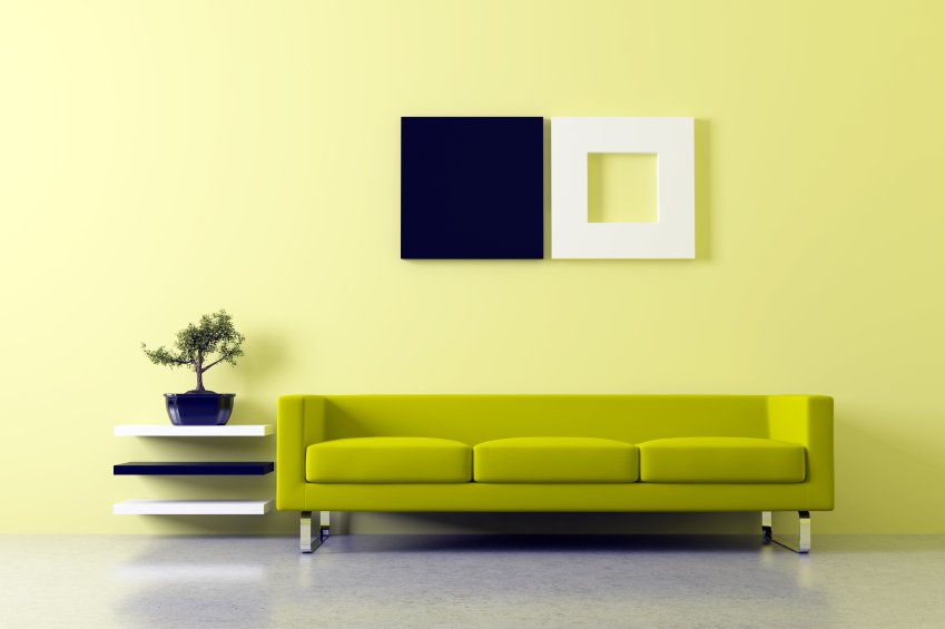 A minimalist living room with a chartreuse sofa and modern wall art, illustrating a space designed for comfort with radiant floor heating.