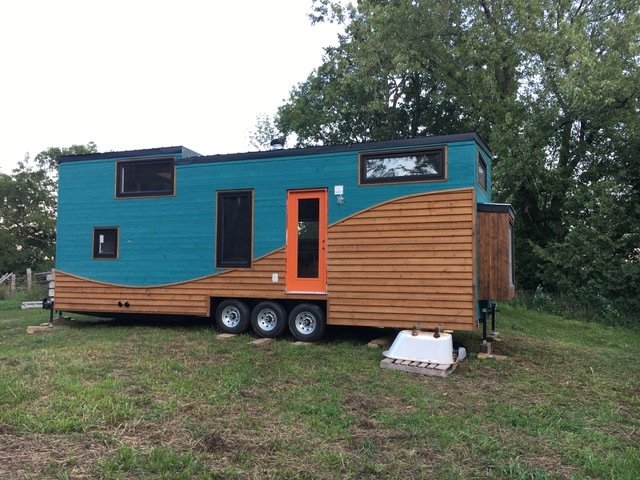 Exterior of a custom tiny house on a trailer featuring concealed electric radiant floor heating.