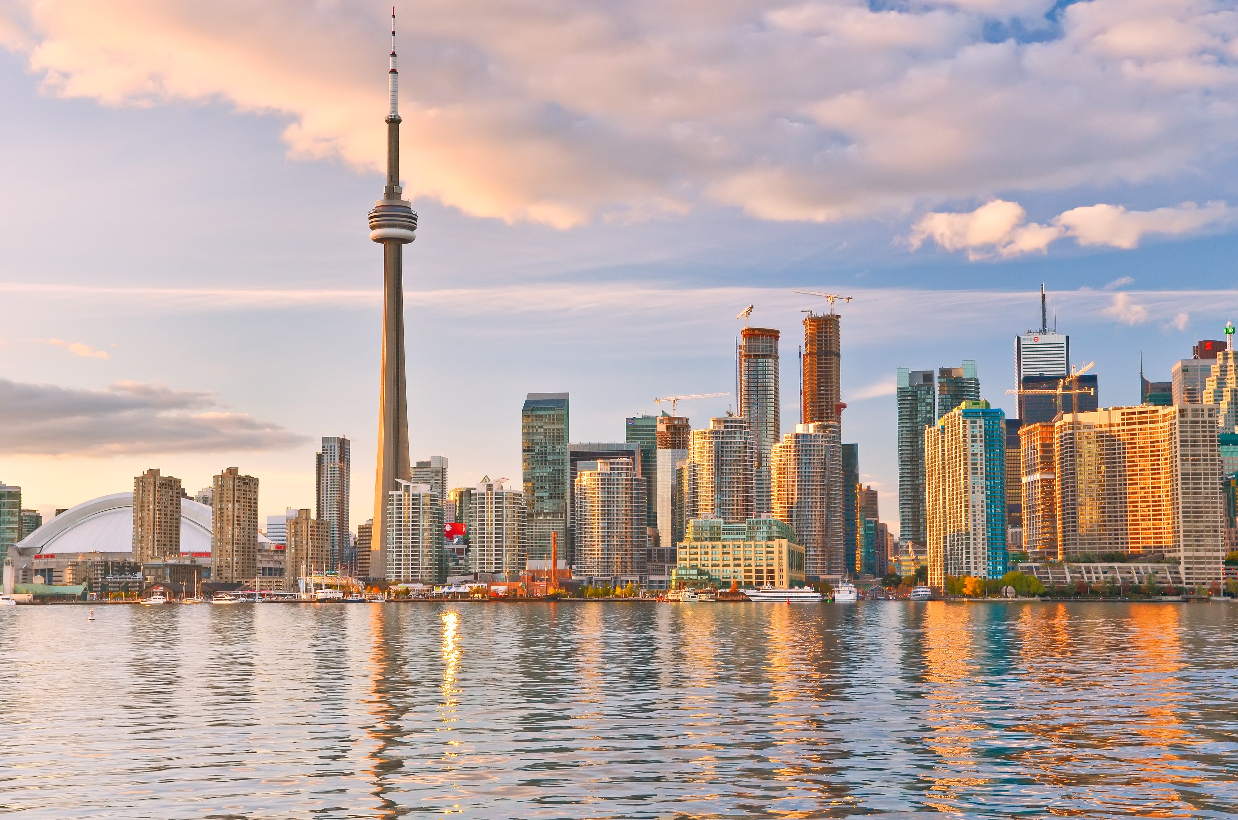 The Toronto city skyline at dusk with the CN Tower and waterfront skyscrapers reflected in the water for a kitchen floor heating blog.