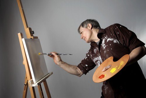 An artist painting on a canvas in a home studio space converted from a garage.