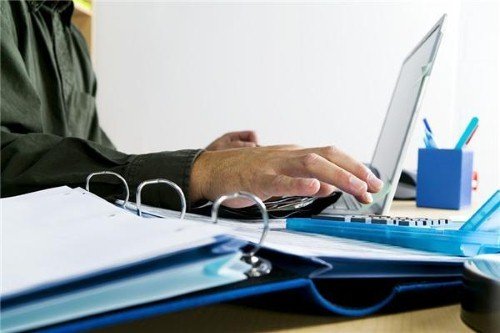 A person working on a laptop at a desk in a home office converted from a walk-in closet.