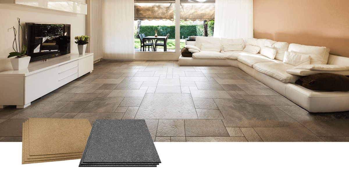 Stacks of tan cork and dark grey synthetic underlayment sheets positioned in a modern living room with tiled flooring.