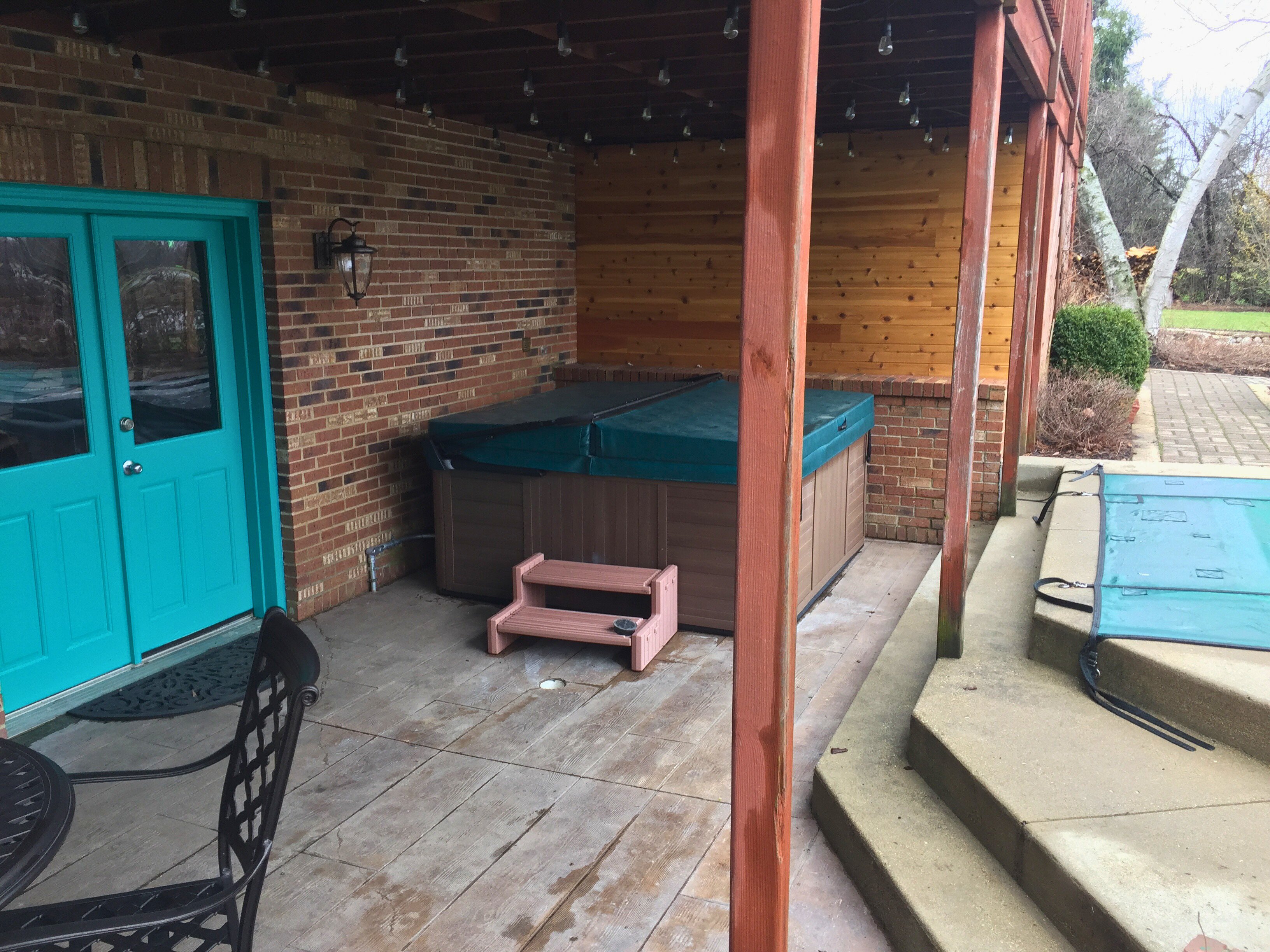 A finished outdoor concrete patio with an integrated snow melting system installed beneath the pavers near a pool and spa.