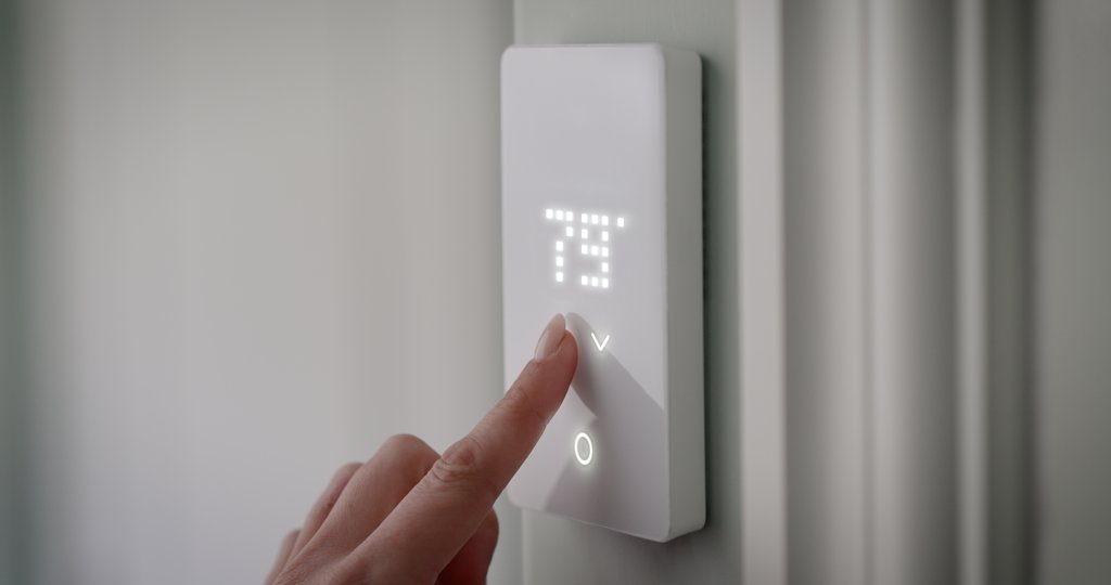 A hand adjusting the temperature on an nTrust 2.0 non-programmable thermostat for an electric radiant floor heating system.