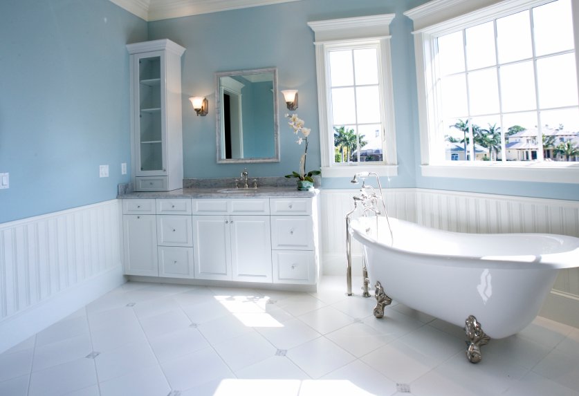A vintage-style bathroom with a white clawfoot bathtub, marble-topped vanity, and diagonal white tile flooring.