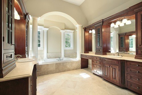 A spacious luxury master bathroom featuring a central drop-in bathtub and large stone tile flooring.