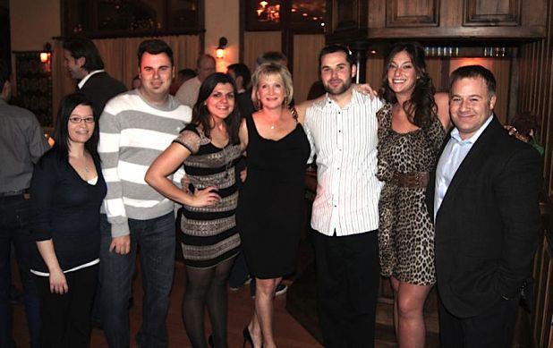 A group of seven WarmlyYours employees smiling together at an evening social event.
