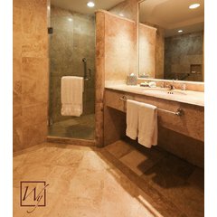 A modern bathroom with beige travertine stone tile flooring and walls, featuring a floating vanity and a glass-door shower enclosure.