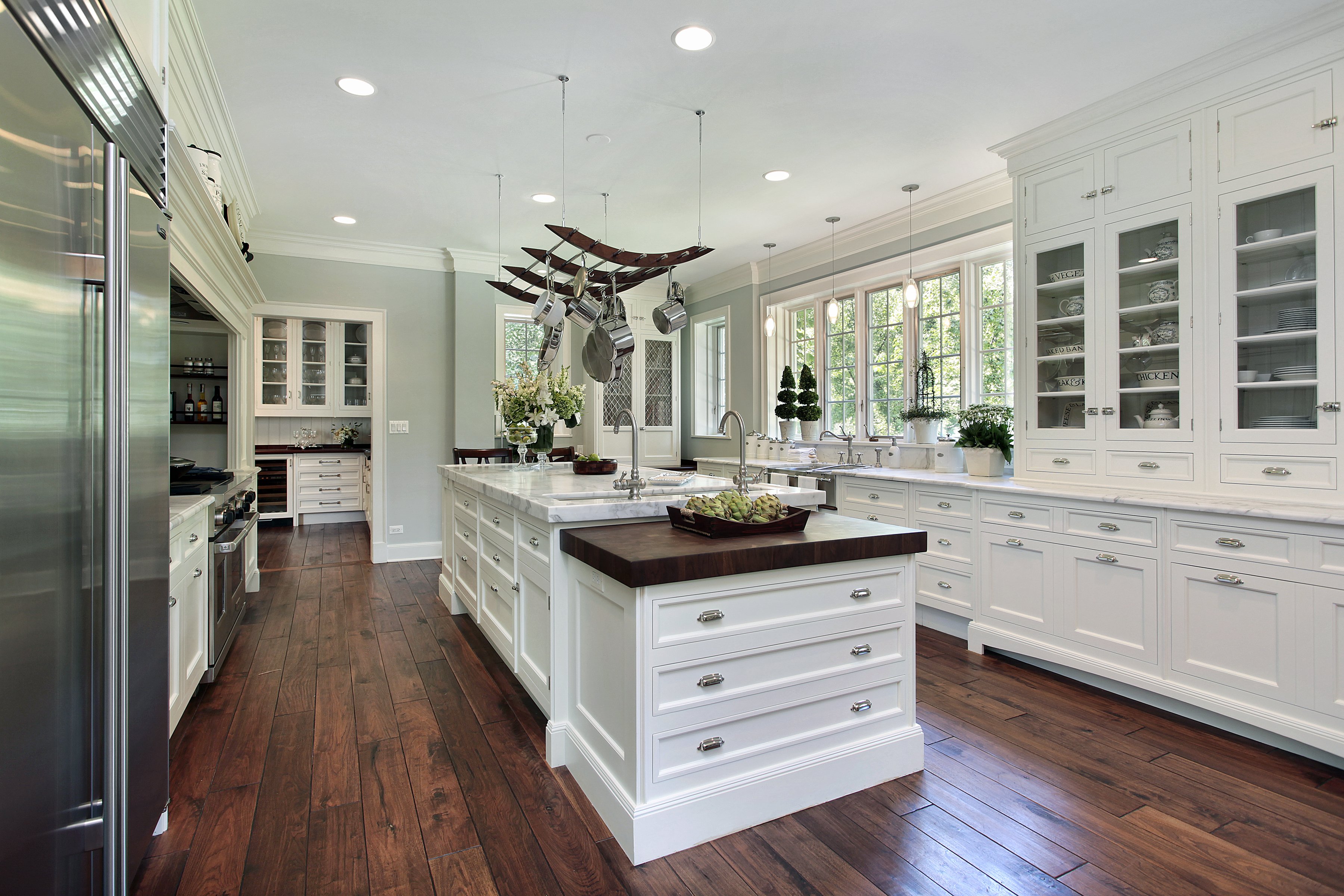 A spacious traditional kitchen featuring white shaker cabinetry, marble countertops, and dark hardwood flooring.