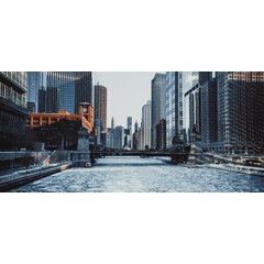 A panoramic view of the frozen Chicago River during winter, featuring a steel bascule bridge surrounded by downtown skyscrapers and architecture.