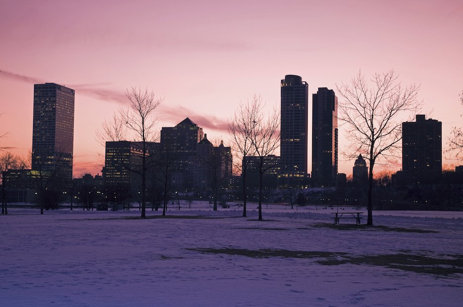 A winter sunset over the Milwaukee city skyline with a snow-covered park in the foreground.