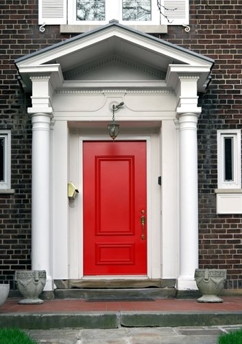 A classic home entryway with a red front door, brick facade, and stone steps that can be kept clear of ice with a snow melting system.