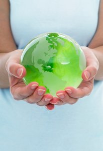 A person holding a translucent green glass globe of the Earth in their cupped hands to represent World Environment Day.
