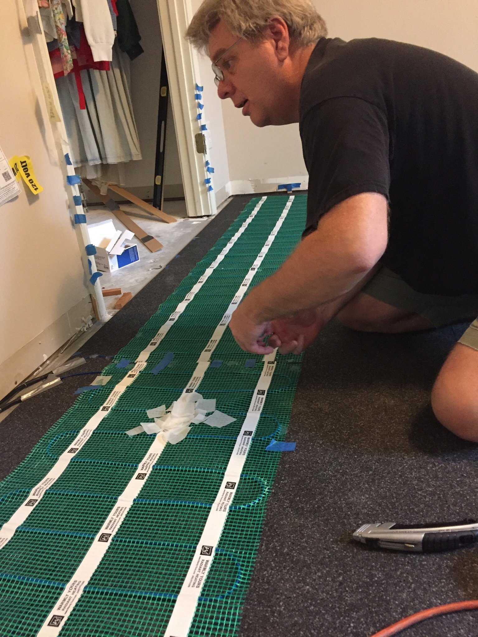 Customer installing floor heating rolls over insulating underlayment