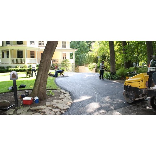 A steam roller compacts the final layer of asphalt.